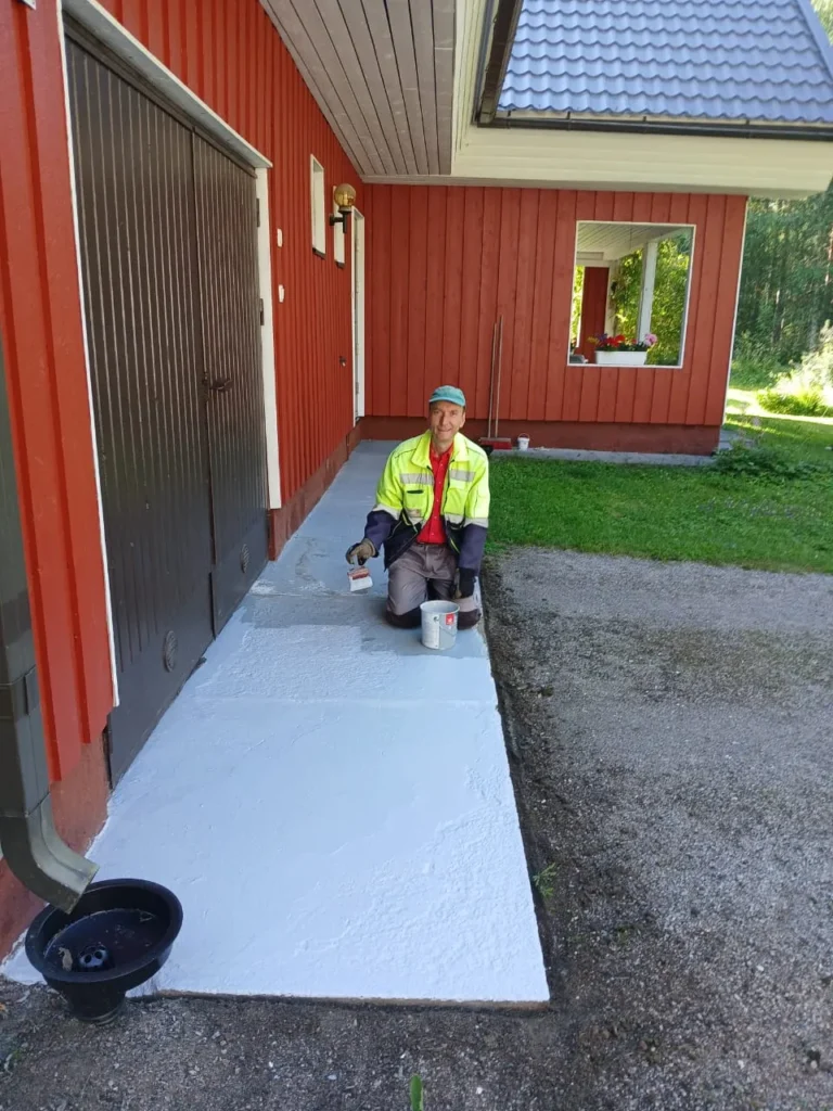 man-painting-driveway-outside-red-house